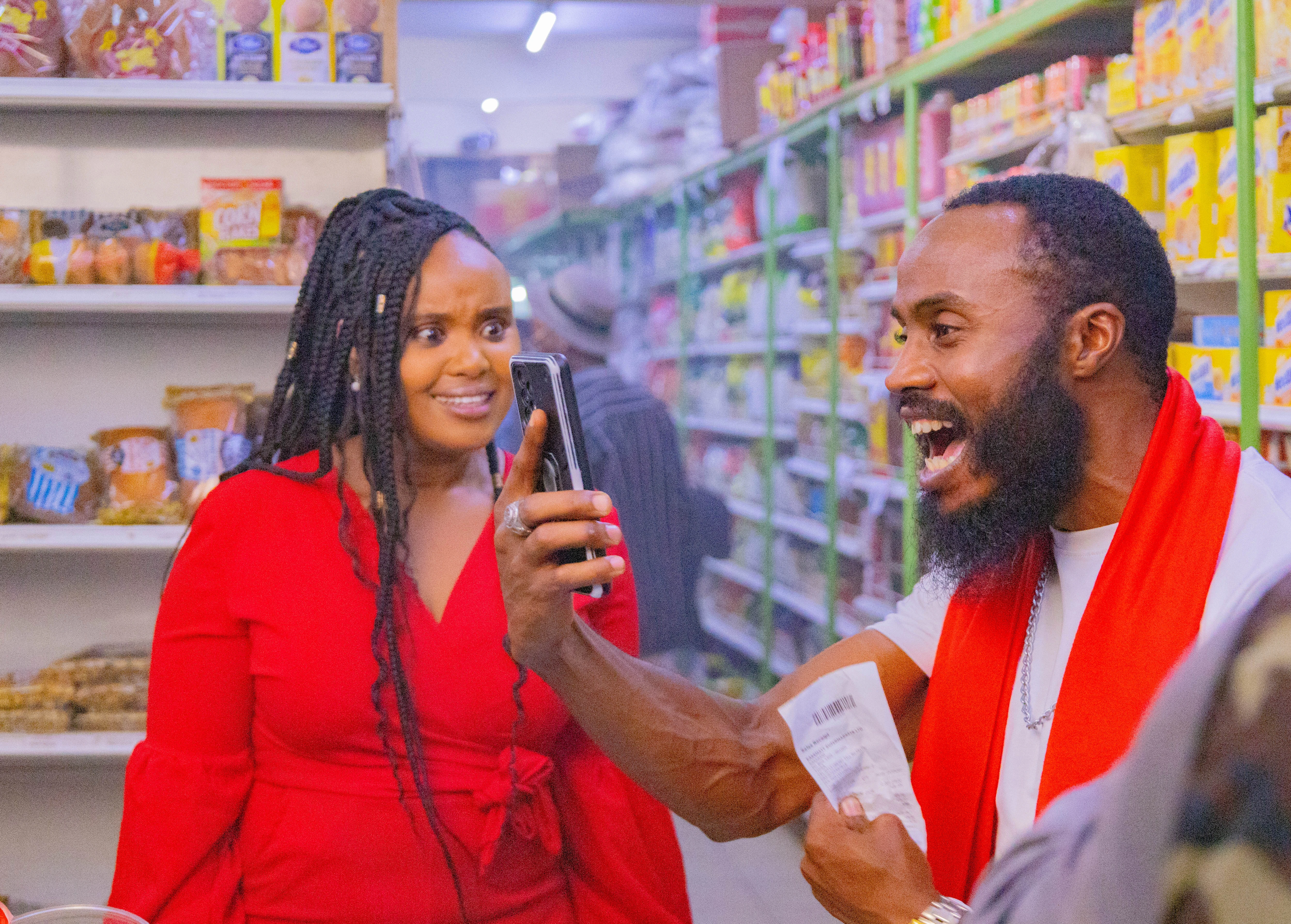 man holds phone in excitement as lady looks on